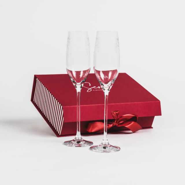 Elegant champagne glasses presented with a sophisticated Scoff box, designed for sparkling wine and celebrations, from The Savoy Shop.