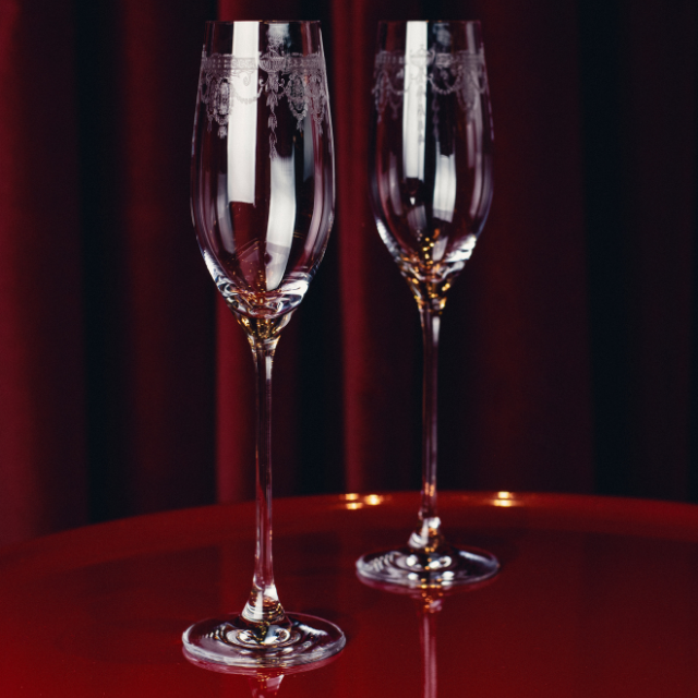 Elegant champagne glasses with slender stems and clear glass bowls, designed for sparkling wine and celebrations, from The Savoy Shop.